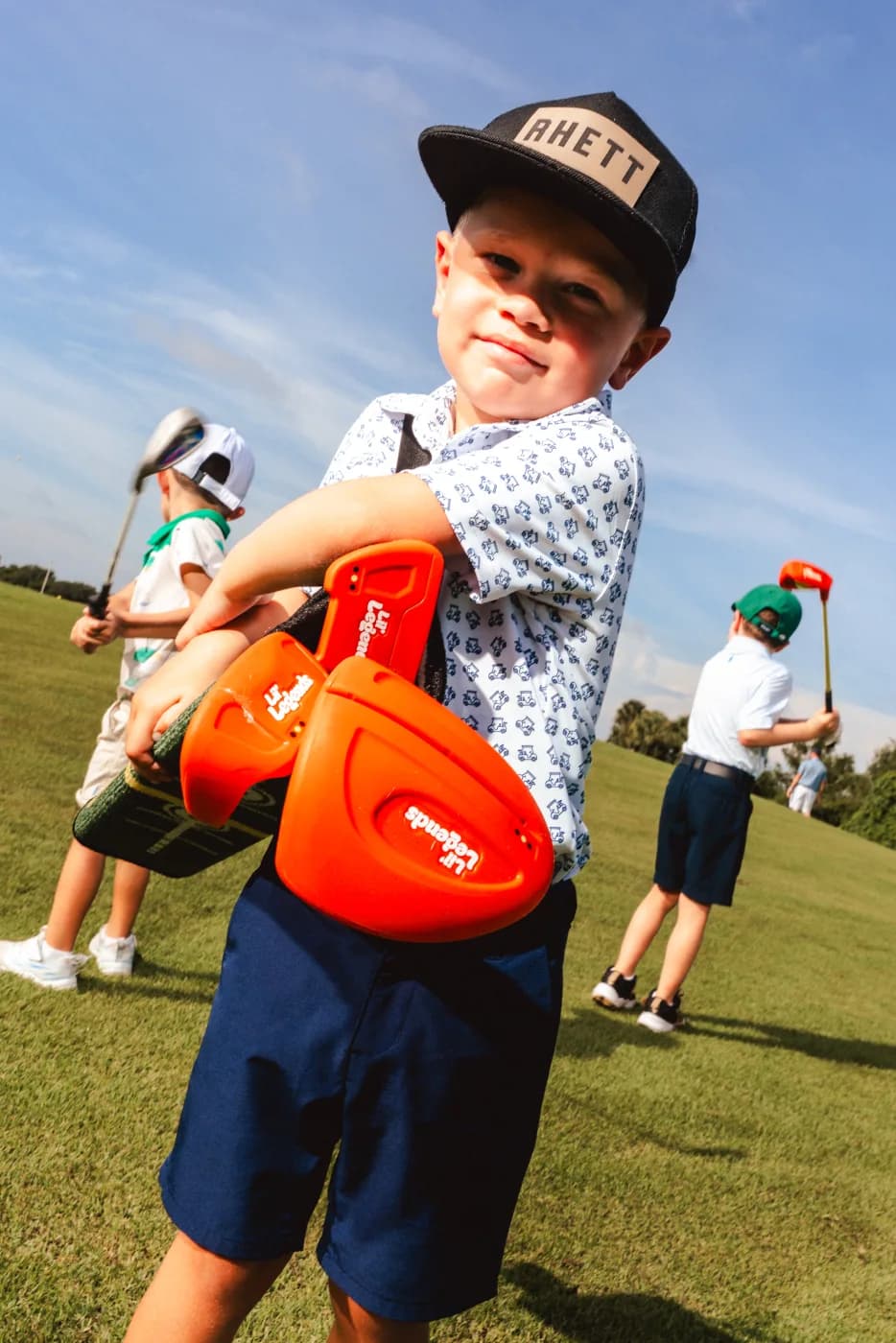 Toddler carrying the Lil' Legends clubs and rolled mat
