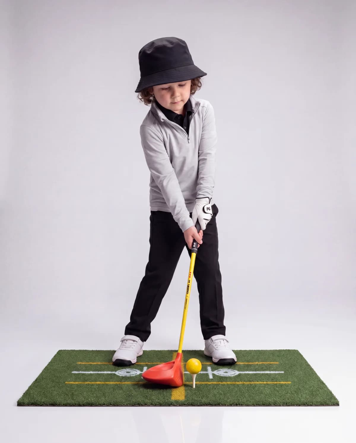 Toddler at address with a yellow ball on the See & Stand Mat