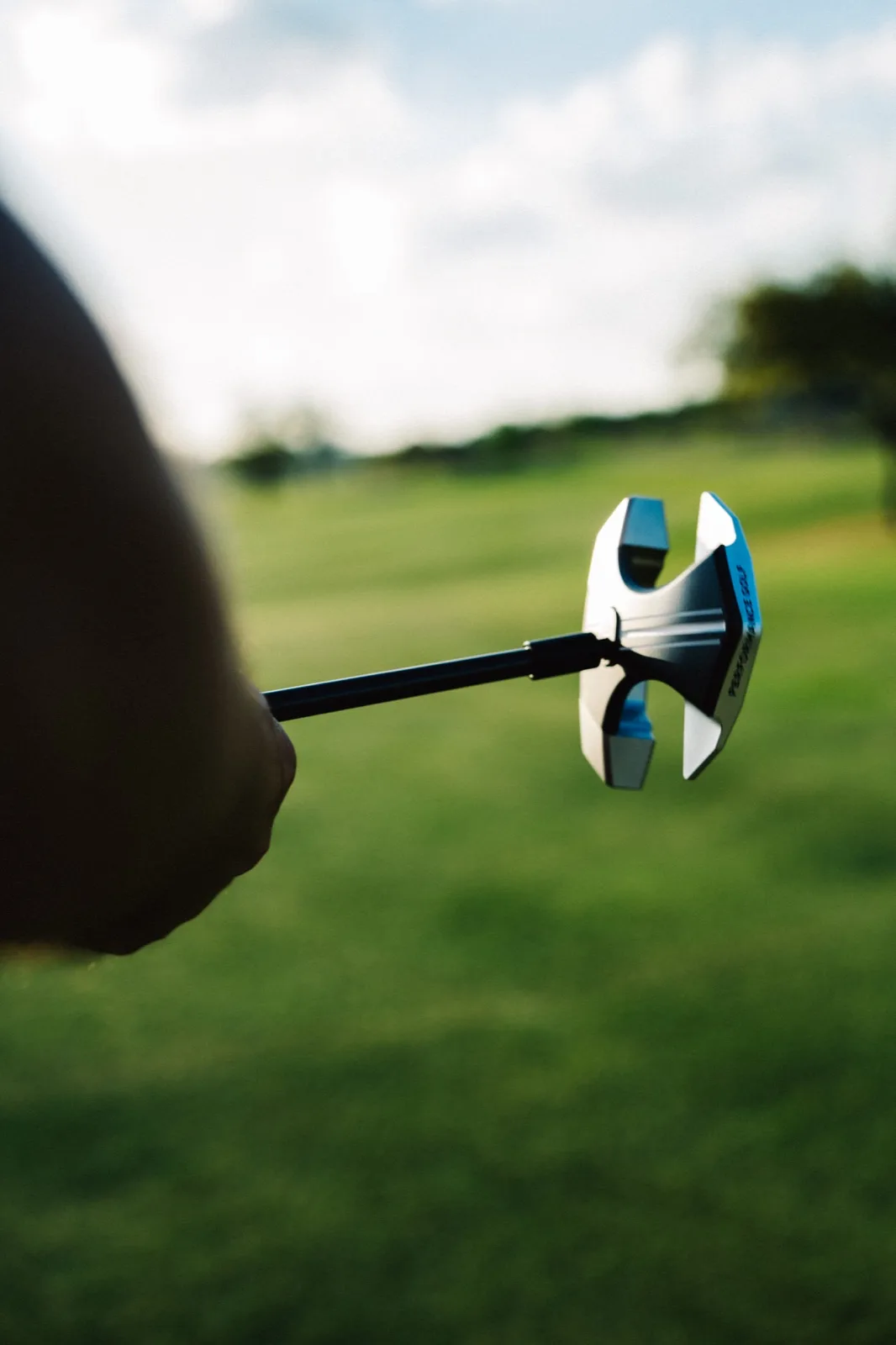 Golfer crouching to read putt at golden hour