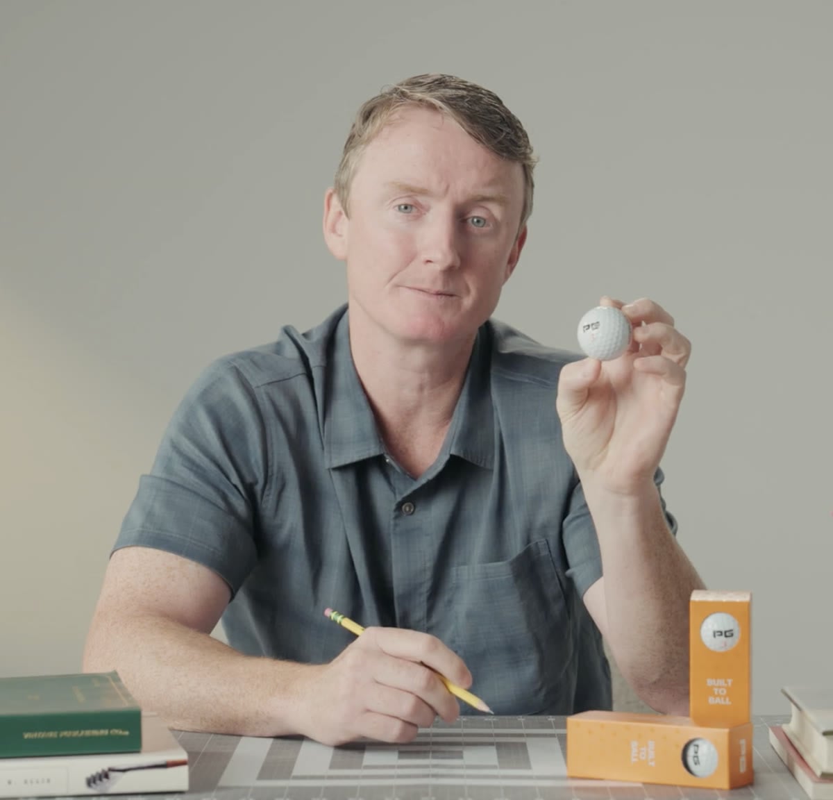 Joe King at his workbench holding an iON+ ball, sleeve boxes beside him