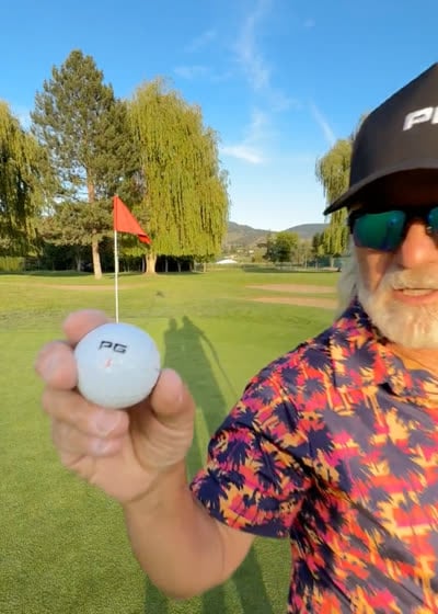 Golfer holding up an iON+ ball beside the flag