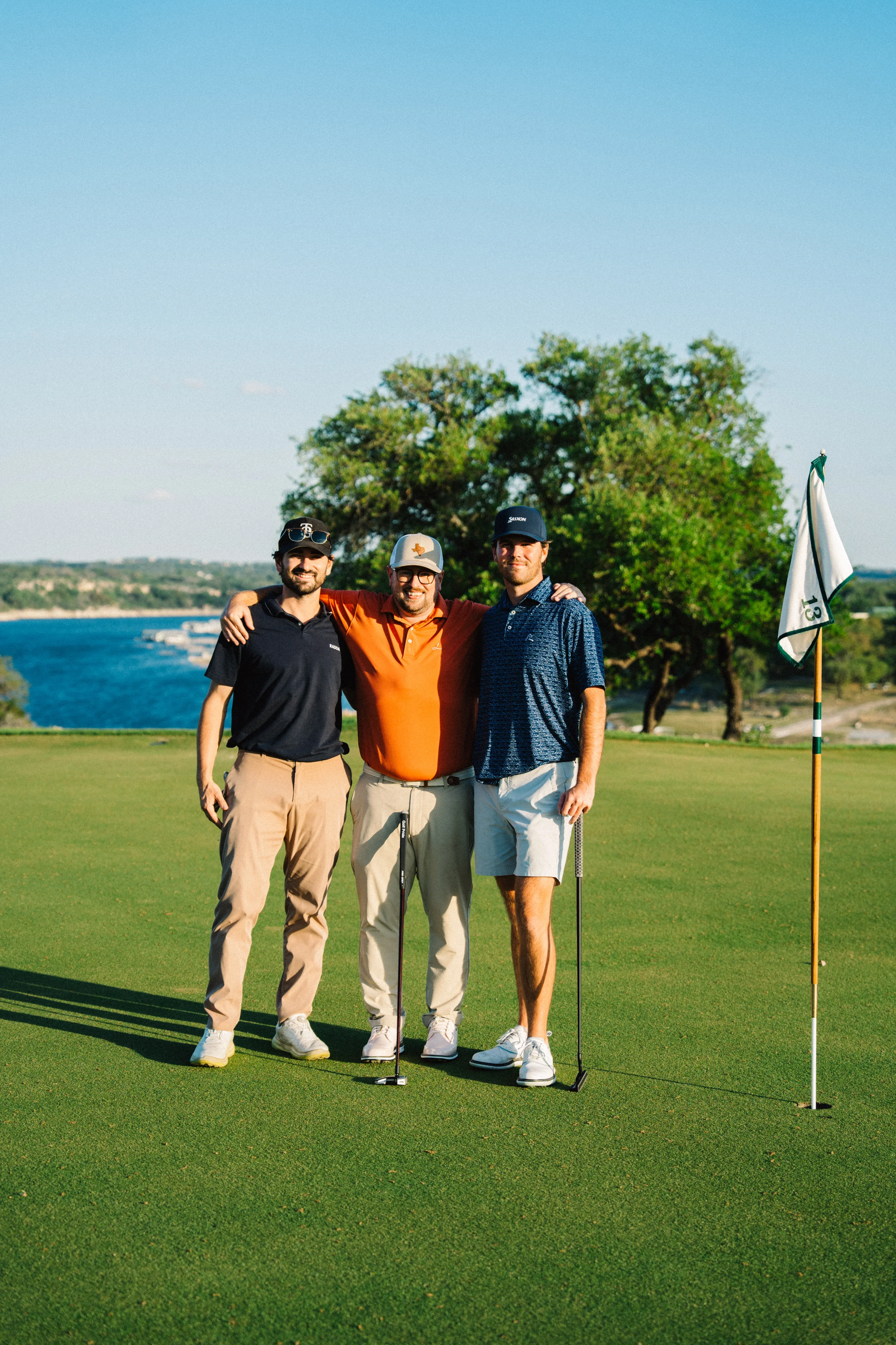 Three golfers by the flag on the green