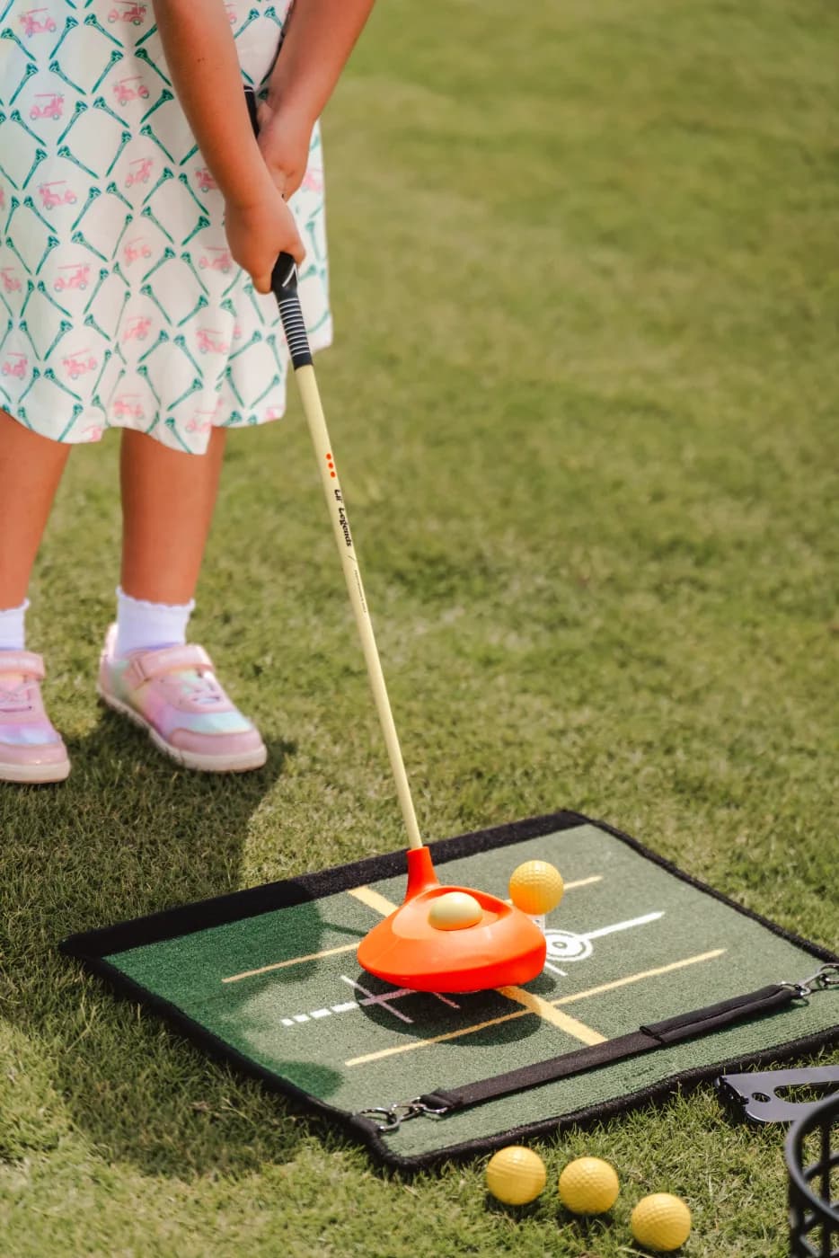Young golfer in a bucket hat standing on the See & Stand Mat at address