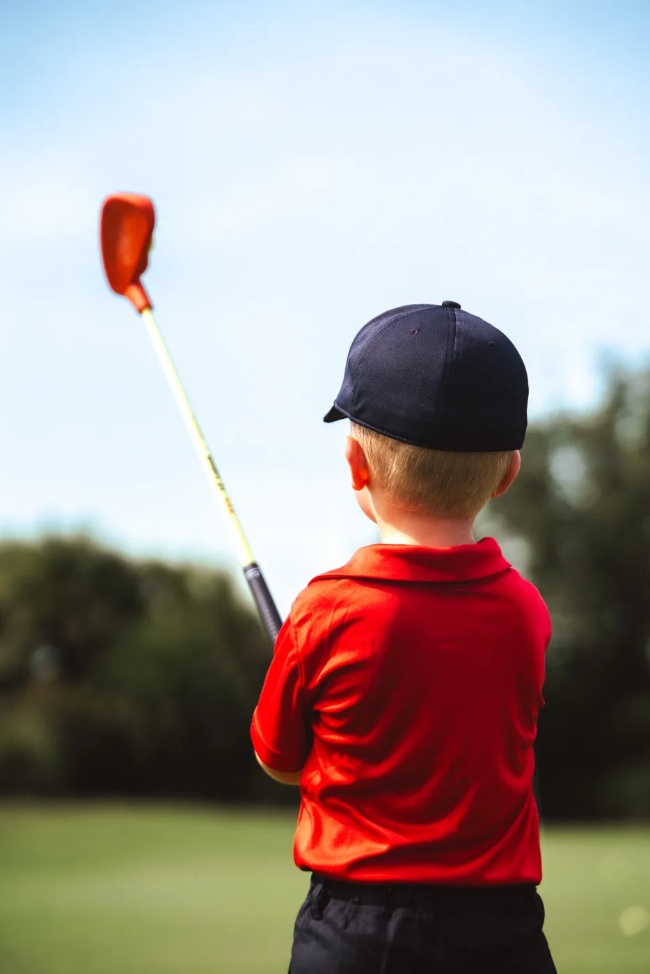 Toddler admiring his club against the sky